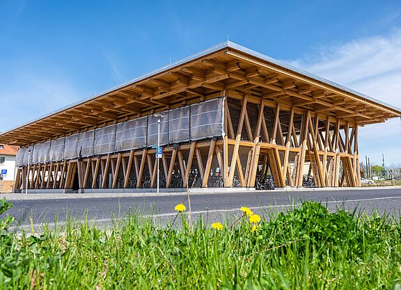 Fahrradparkhaus Eberswald Eine Fahrradparkhaus in Holzkonstruktion vor blauem Himmel und grüner Wiese