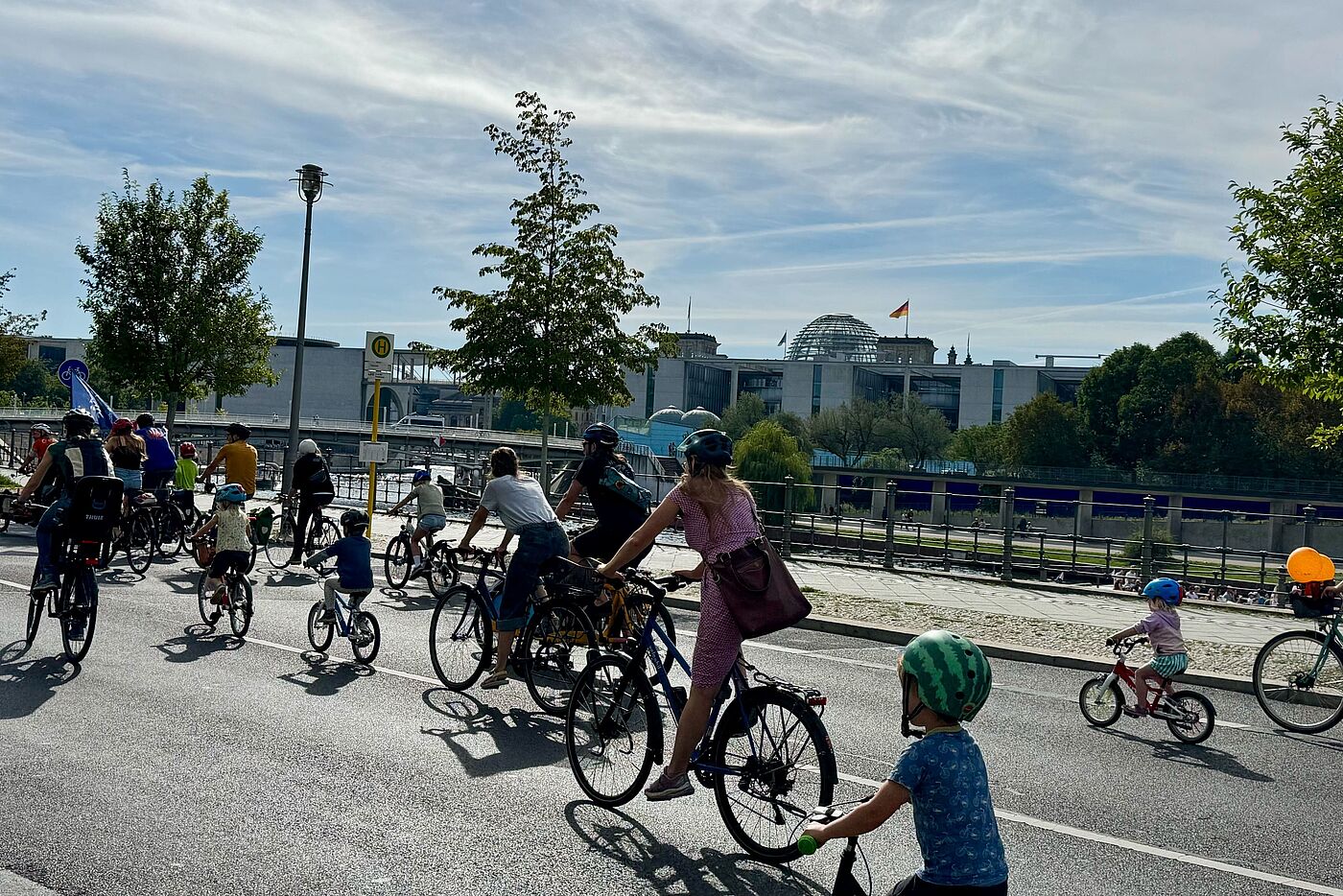 Kinder und Erwachsene fahren Fahrrad im Hintergrund der Bundestag