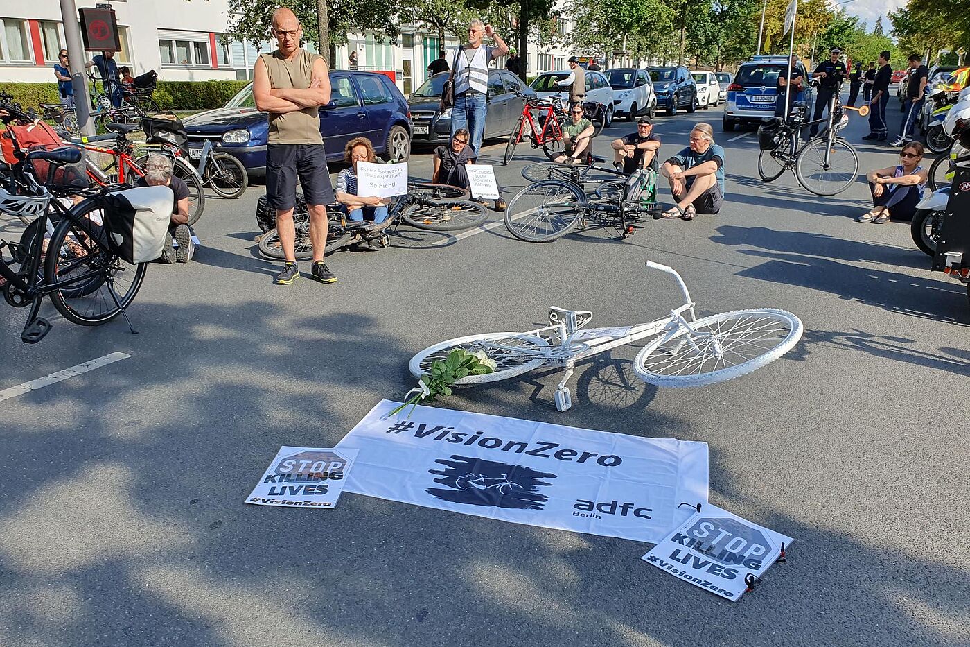 Mahnwache für die getötete Radfahrerin in Marienfelde Menschen sitzen bei einer Mahnwache auf dem Boden um ein weißes Fahrrad