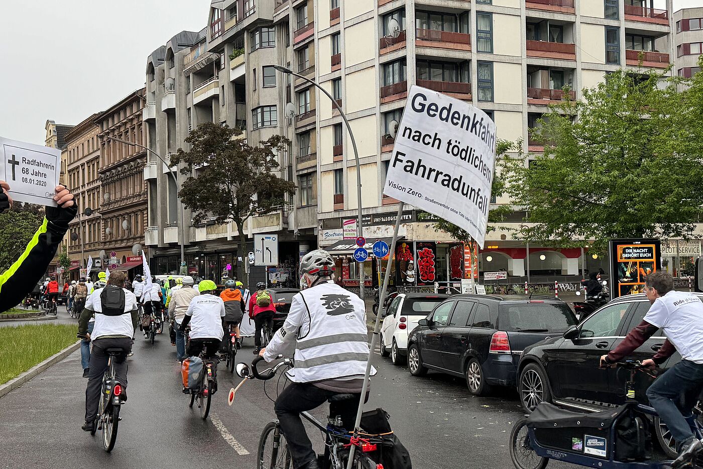 Mensch hält zum Gedenken an 2020 getötete Radfahrerin ein Schild bei Fahrraddemonstration in die Luft