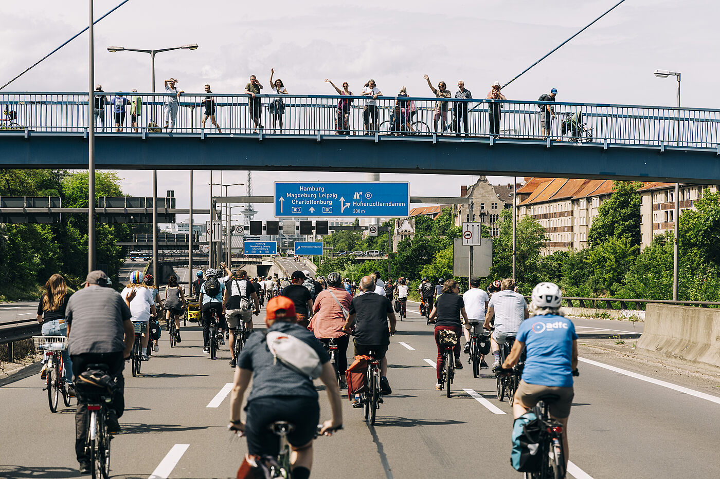 Menschen auf einer Brücke schauen auf die Fahrradsternfahrt auf der Autobahn