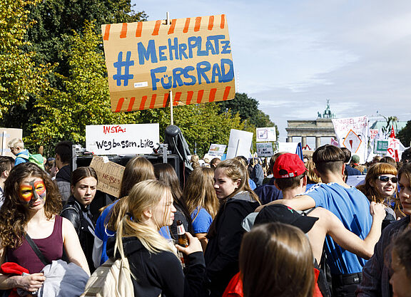 Teilnehmende halten bei einer Demo ein Schild hoch.