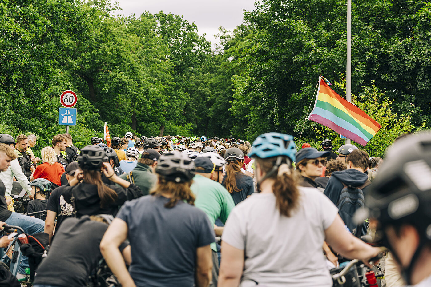 Radfahrerinnen mit Helm von hinten und eine Regenbogen Fahne