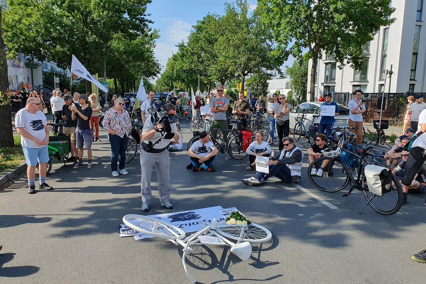 Mahnwache für die getötete Radfahrerin in Marienfelde Menschen sitzen bei einer Mahnwache auf dem Boden um ein weißes Fahrrad