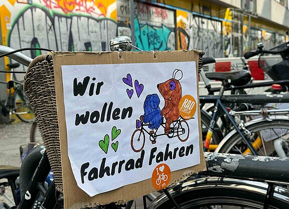 Selbstgemaltes Schild an Fahrrad mit der Maus und Elefanten auf dem steht: Wir wollen Fahrrad fahren