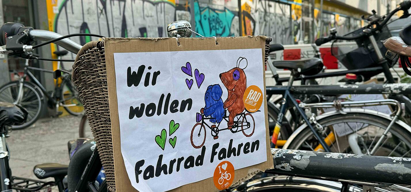 Selbstgemaltes Schild an Fahrrad mit der Maus und Elefanten auf dem steht: Wir wollen Fahrrad fahren