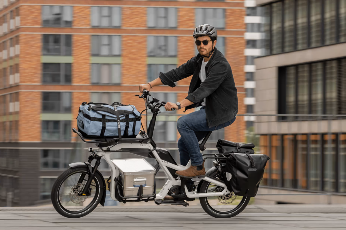 CaGo Eine beladenes CaGo Lastenrad auf der Straße, gefahren von einem Mann.