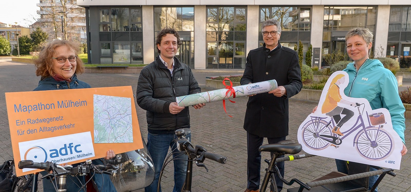 Vier Personen übergeben einen Stadtplan an Vertreter der Stadtverwaltung